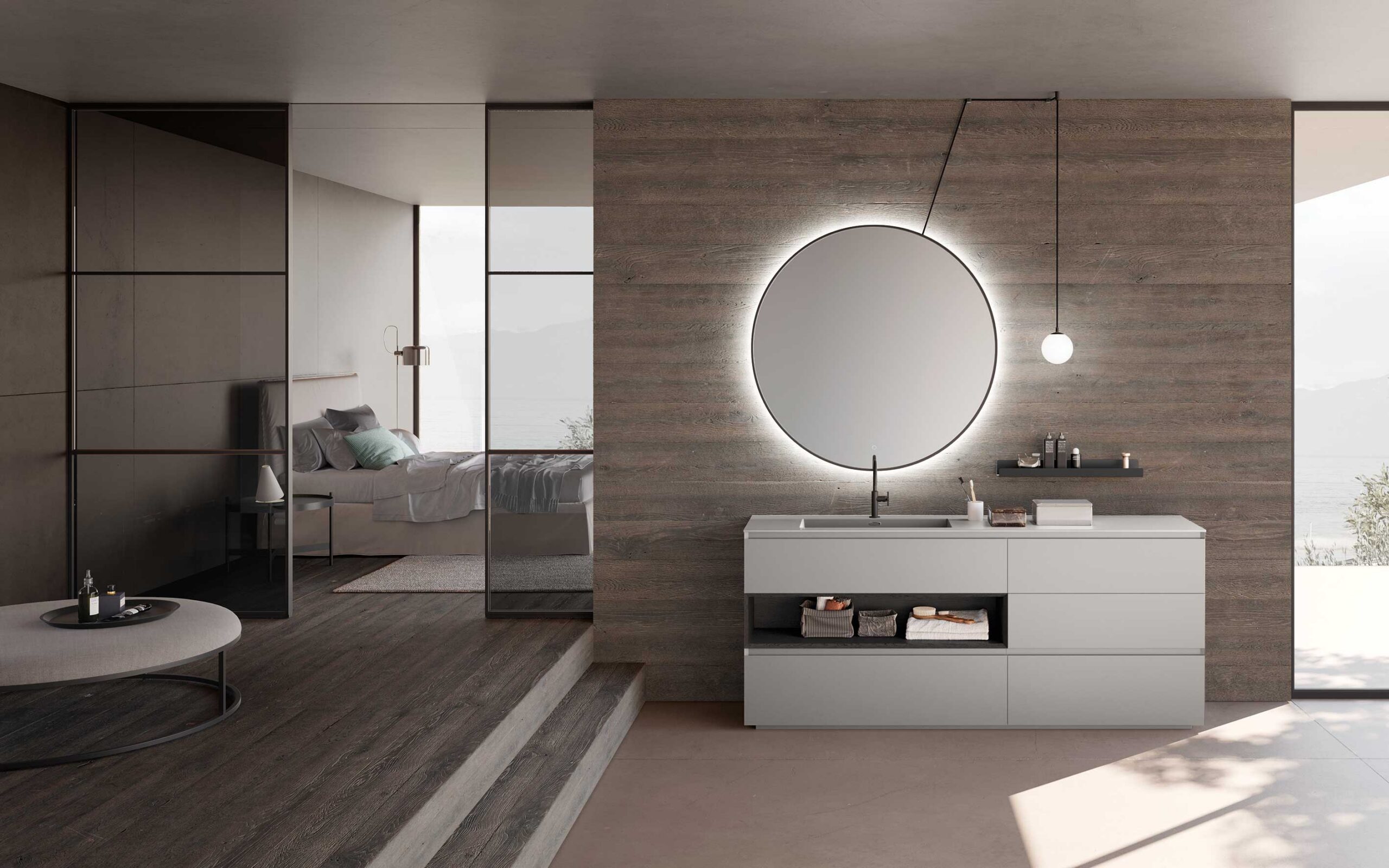 Bagno en suite dal design contemporaneo con mobile a terra bianco, specchio rotondo retroilluminato e parete effetto legno. Separazione degli spazi con parete a vetro.