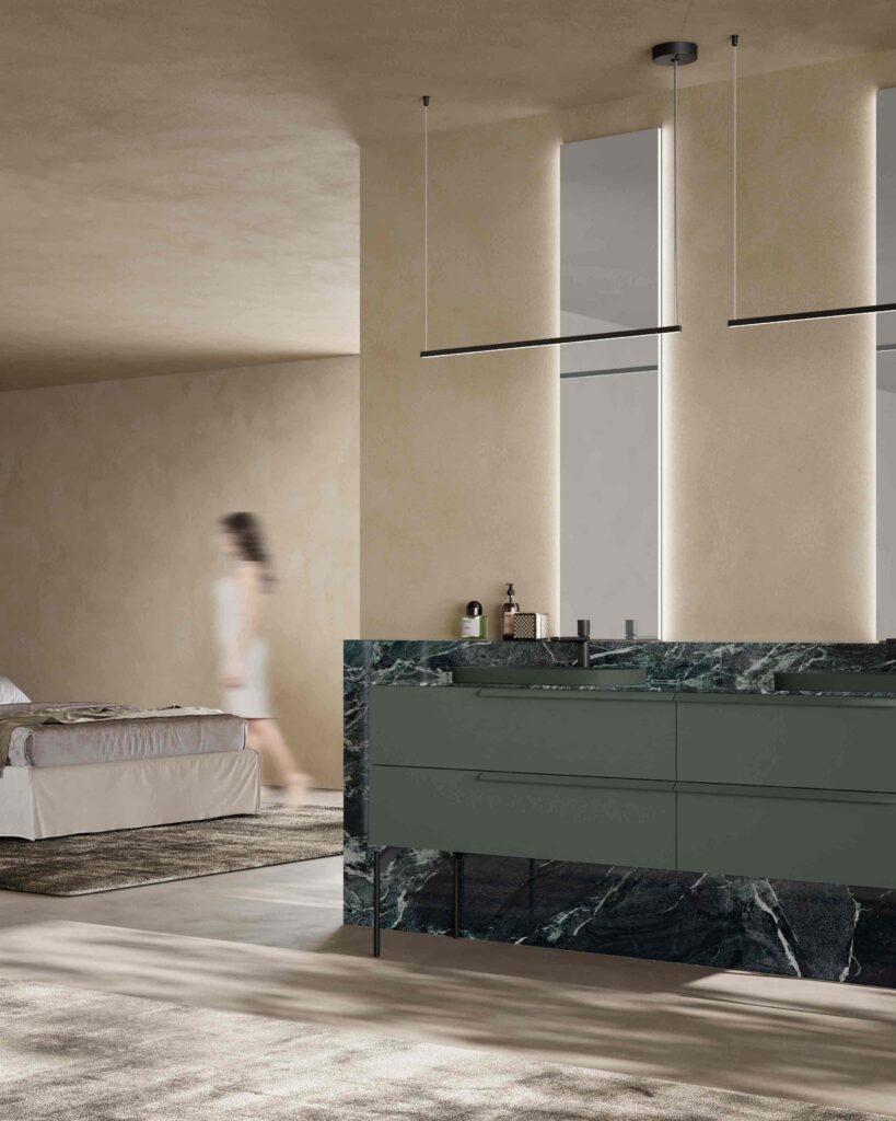 Bagno en suite aperto sulla camera da letto, con mobile bagno verde e piano in marmo davanti a pareti in tonalità sabbia