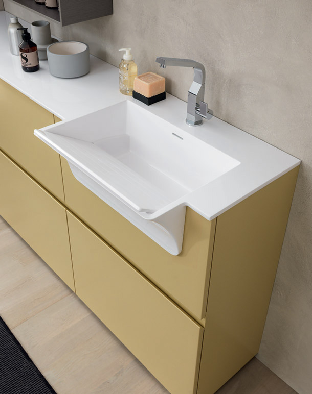 Semi-recessed sink with removable board for washing clothes, integrated into the white top of a mustard yellow cabinet.