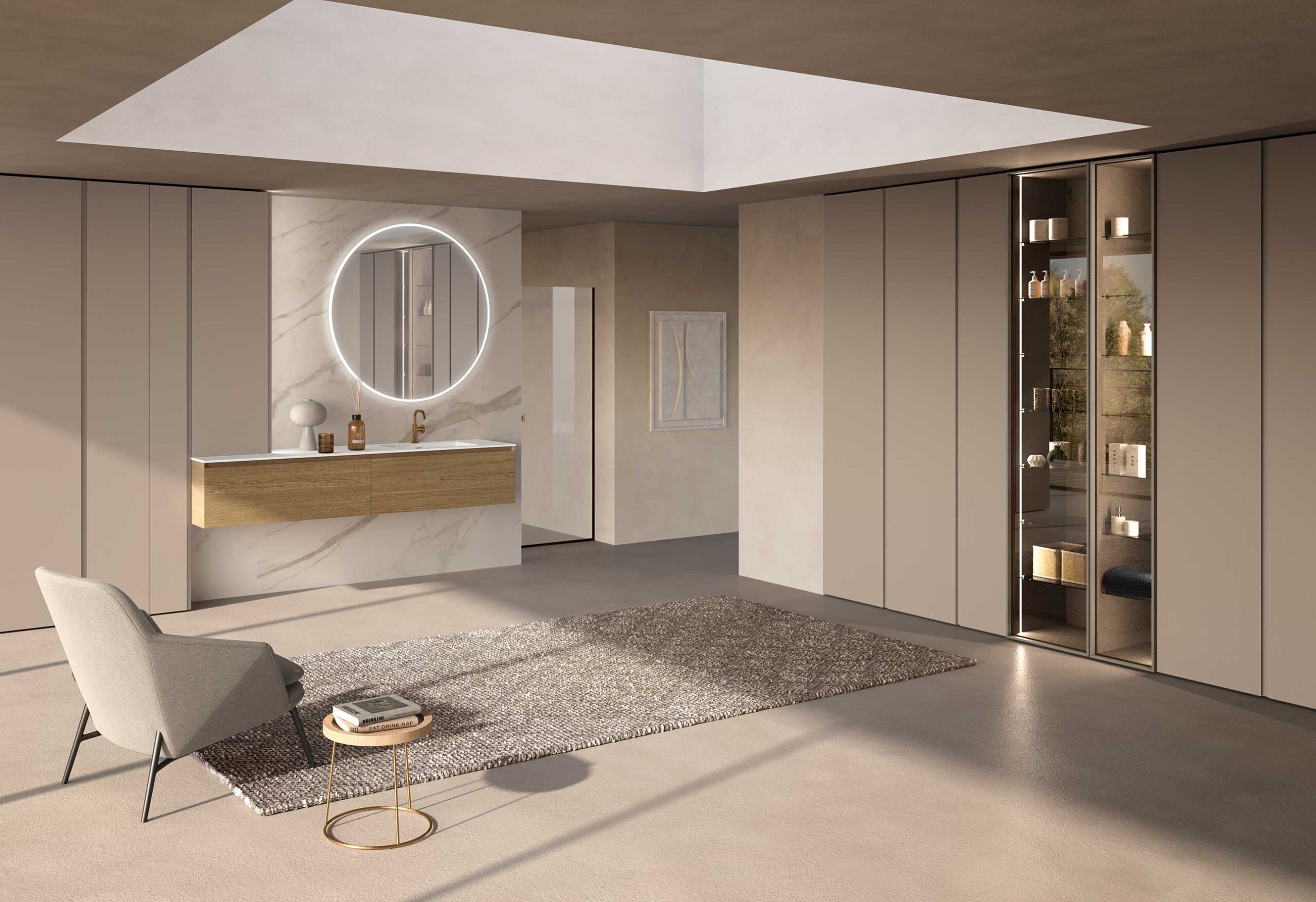 Designer bathroom with suspended base units with wood-effect fronts, light marble wall, large backlit round mirror, full-height beige columns and relaxation area with armchair.