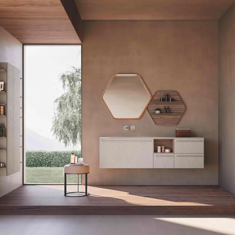 Bagno moderno minimalista con arredi sospesi, specchio esagonale e luce naturale da una grande vetrata.