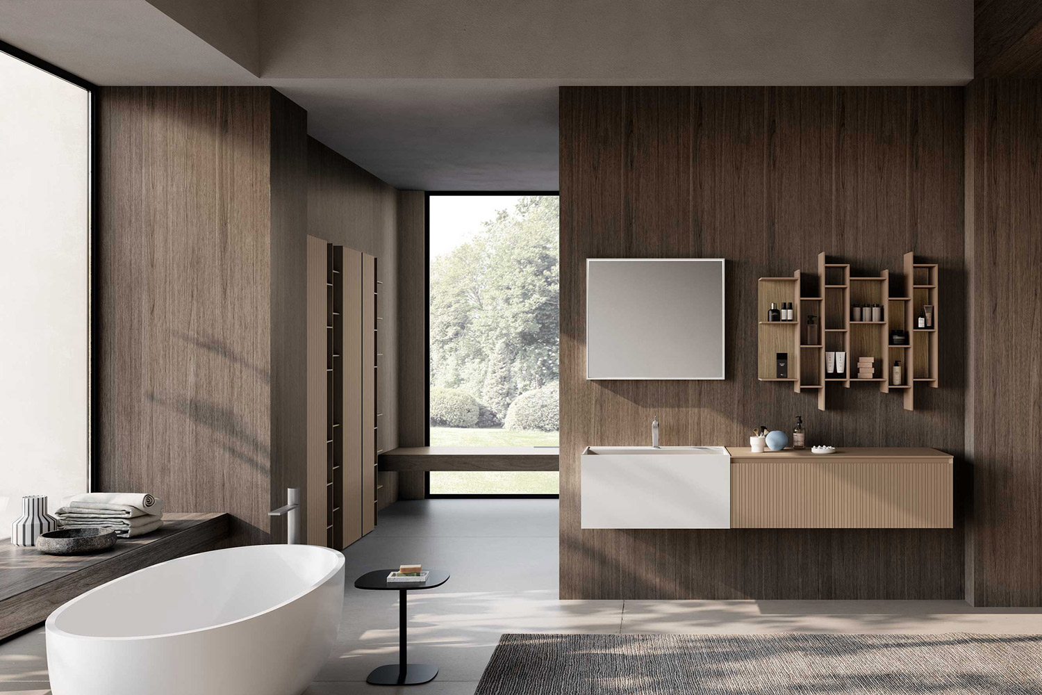 Bagno di design con basi sospese in colore beige e bianco, specchio rettangolare e pensili con aperture a giorno abbinati alle basi in colore beige. Sulla sinistra una vasca vasca freestanding bianca e in secondo piano delle colonne beige tra le pareti rivestite in legno scuro. Sullo sfondo un’ampia vetrata con vista sul giardino.