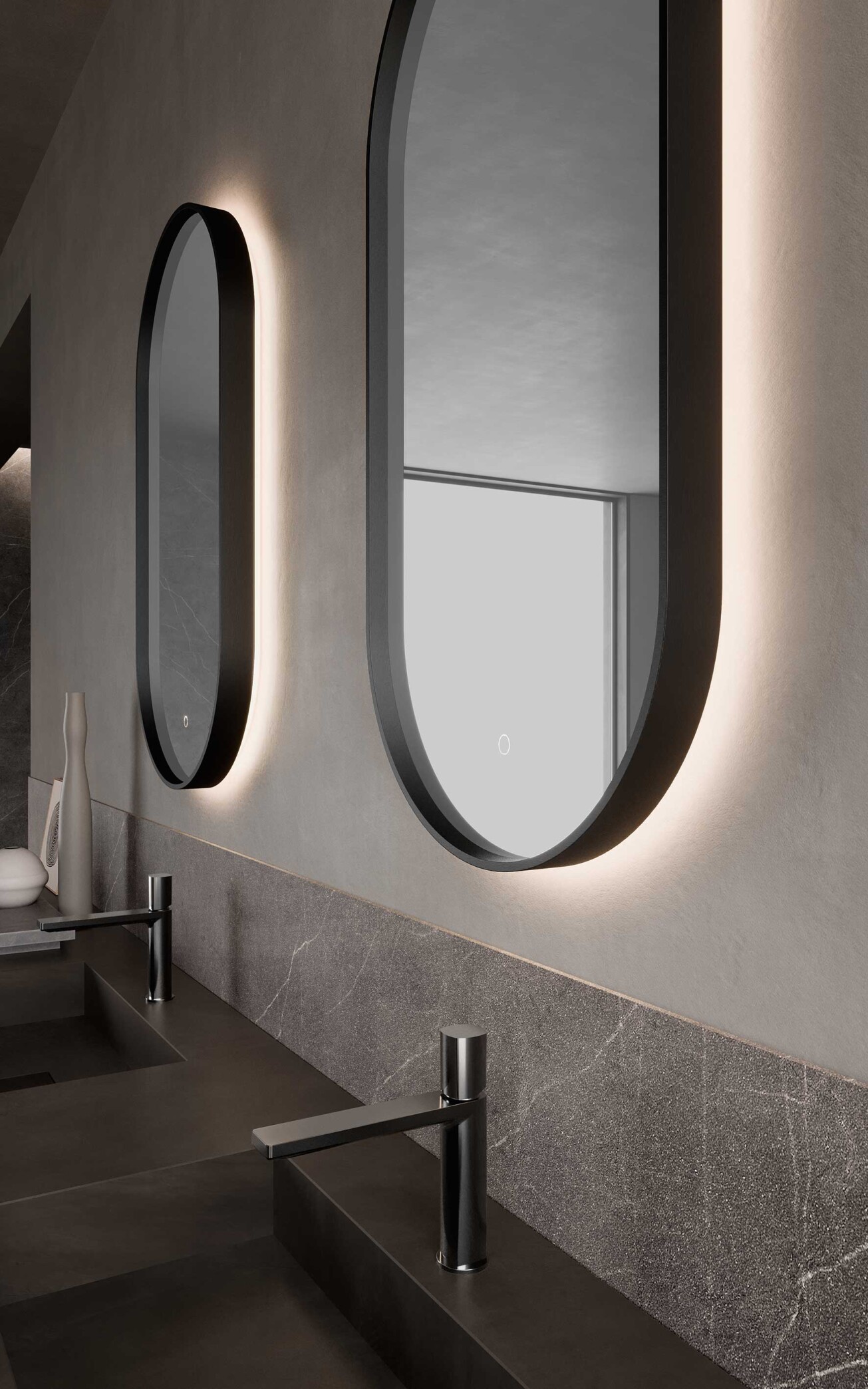 Dettaglio di specchi bagno ovali retroilluminati con cornice nera e rubinetteria nero opaco su top scuro in un ambiente bagno dal design moderno.