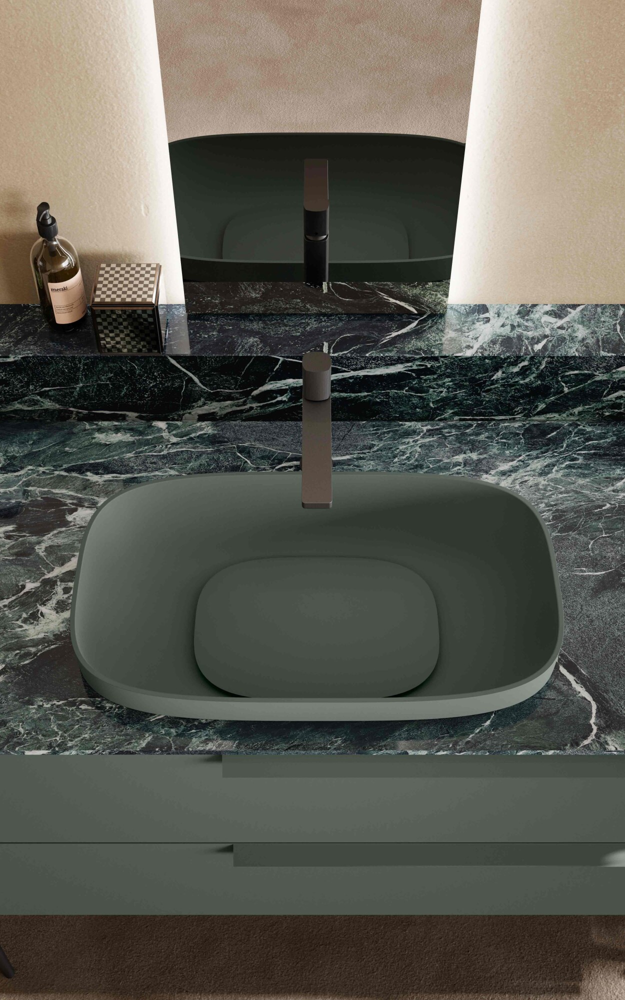 Primo piano di un lavabo da appoggio verde opaco su top effetto marmo verde, con rubinetteria nera e specchio retroilluminato per un bagno dal design contemporaneo.
