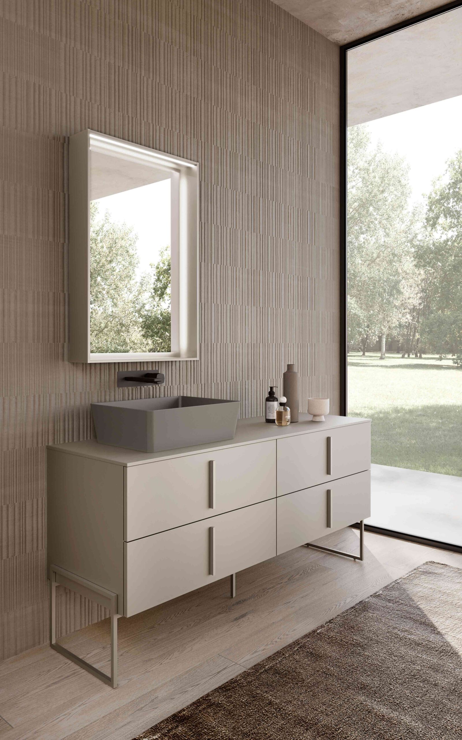 Lavabo d’appoggio rettangolare su mobile bagno con cassetti, specchio illuminato e rubinetteria a parete.
