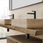 Doppio lavabo d’appoggio rettangolare su piano sospeso in legno, con rubinetteria nera in un bagno moderno.